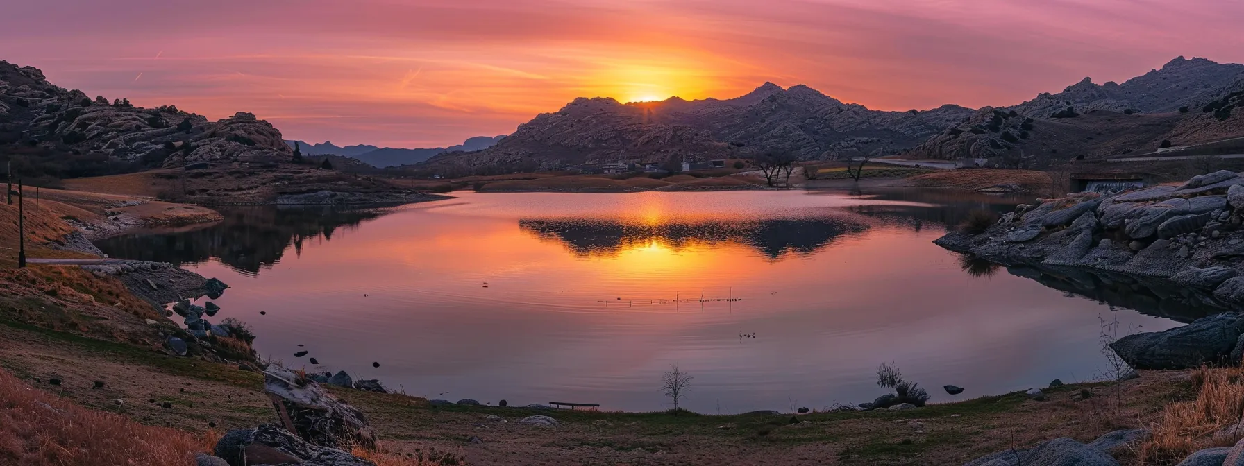 ein majestätischer sonnenuntergang über einer ruhigen berglandschaft, in der sich lebendige farben von orange und pink im klaren wasser eines glitzernden sees spiegeln.